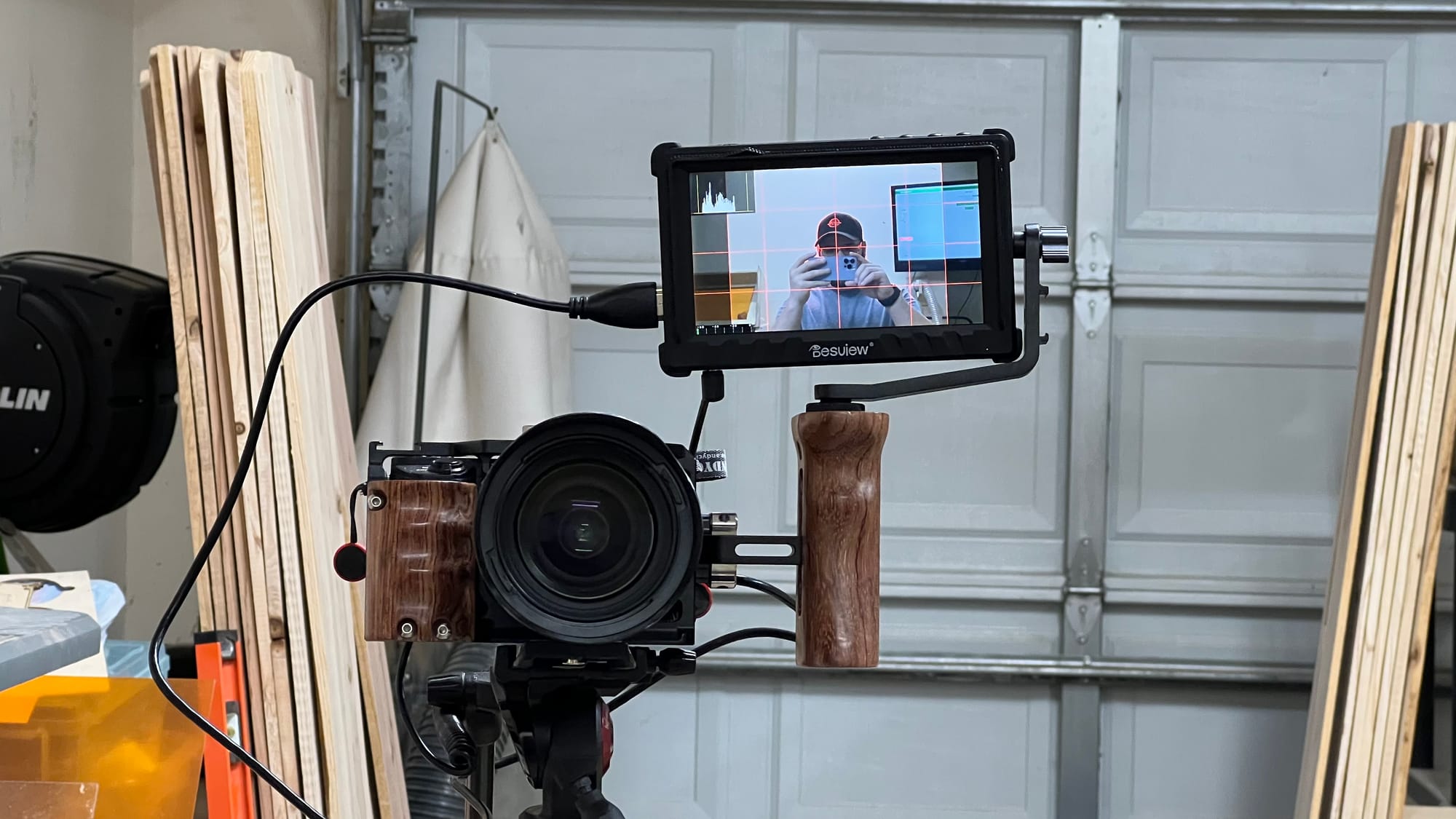 A camera on a tripod with a monitor facing the camera operator and a person visible on the screen.