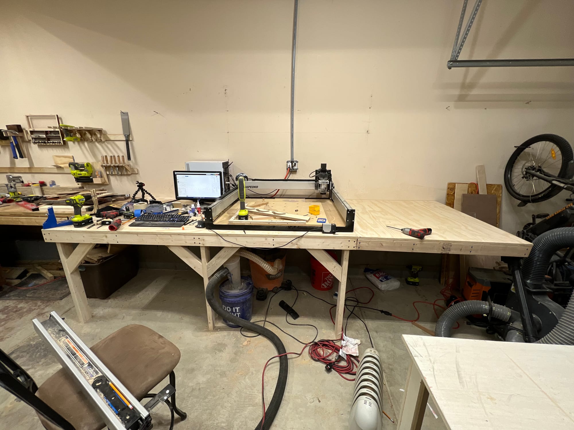 A garage with a Shapeoko 3 XXL CNC sitting on a long workbench.
