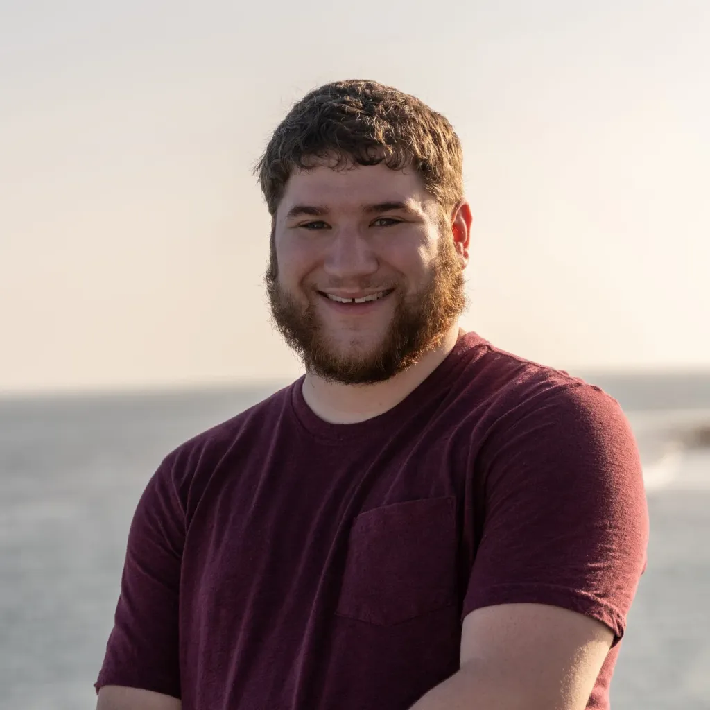 Patrick Campanale smiling outdoors in a maroon T-shirt